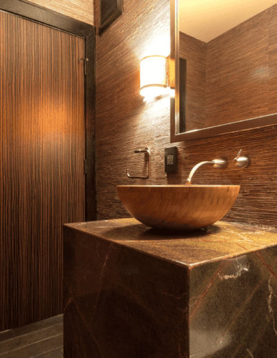 Modern bathroom interior with textured wall, vessel sink, and warm lighting.