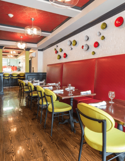 Modern diner interior with red booths, yellow chairs, and decorative plates on the wall.